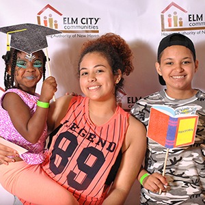 Teenager with young siblings posing in front of an ECC step and repeat